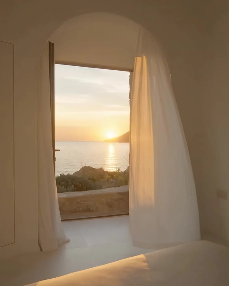 White suite with linen curtains and a broad sea-facing window